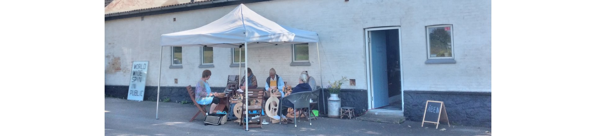 folk der sidder og spinder foran butikken i N�stved